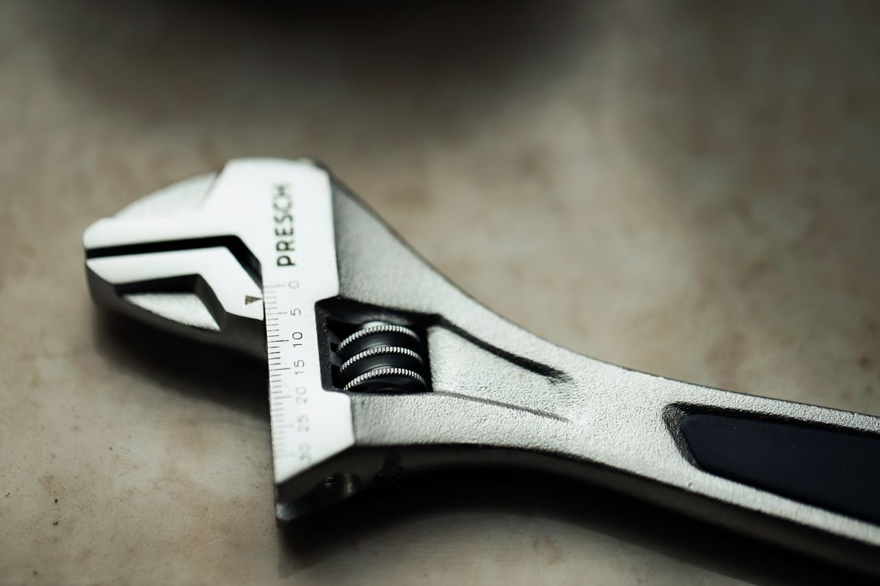 Detailed macro shot of a metallic adjustable wrench placed on a textured surface.
